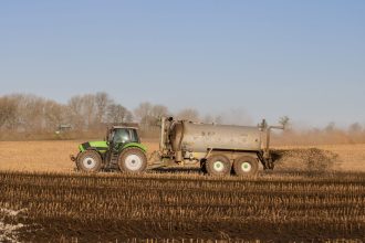 Trator com tanque aplicando fertilizante sobre uma área agrícola.