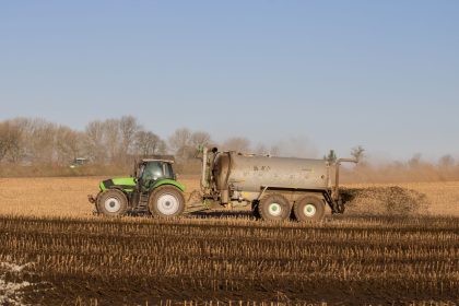 Trator com tanque aplicando fertilizante sobre uma área agrícola.