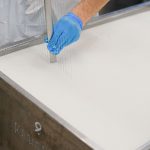 Trabalhador utiliza uma ferramenta durante a produção artesanal de queijo em uma unidade de laticínios.