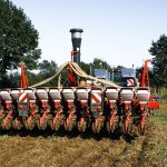 Máquina agrícola semeia uma lavoura em campo aberto.