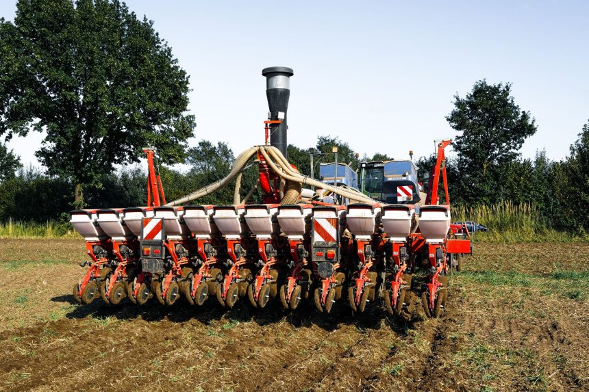 Máquina agrícola semeia uma lavoura em campo aberto.
